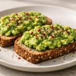 Creamy mashed avocado spread over toasted low-carb bread, finished with simple seasoning.