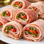Layered deli meats and cheese rolled tightly with fresh fillings, sliced into compact pieces that hold their structure without bread.