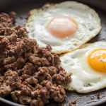Crispy ground beef and fried eggs cooked together in a hot skillet for a simple high-protein keto meal.